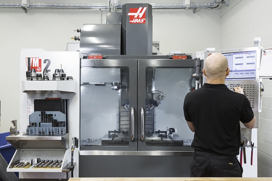 Qtechs prototypverkstad — HAAS VM2 5-axlig CNC-fräs där tekniker övervakar körning